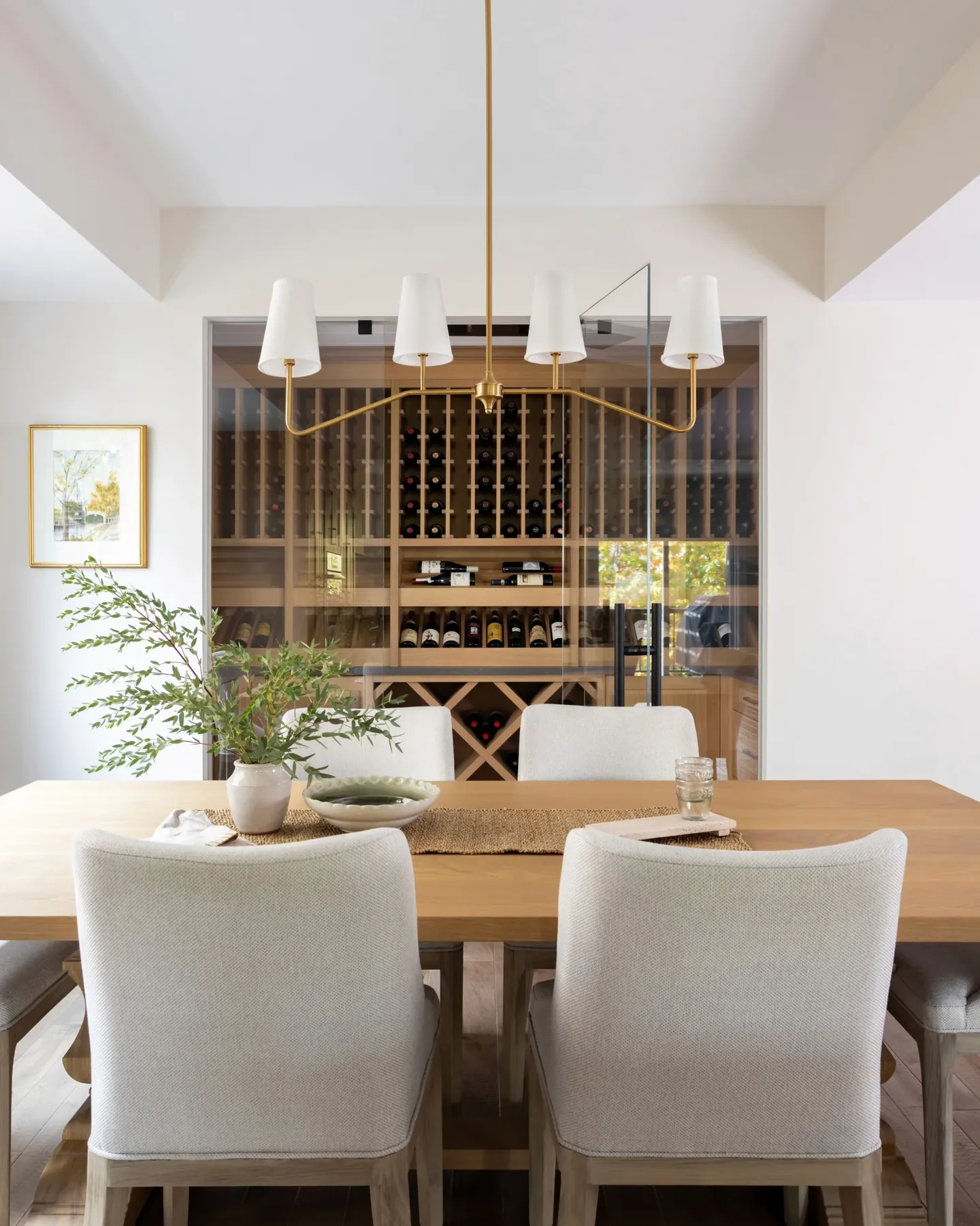 Dining room with a glass-fronted wine wall and a brass chandelier