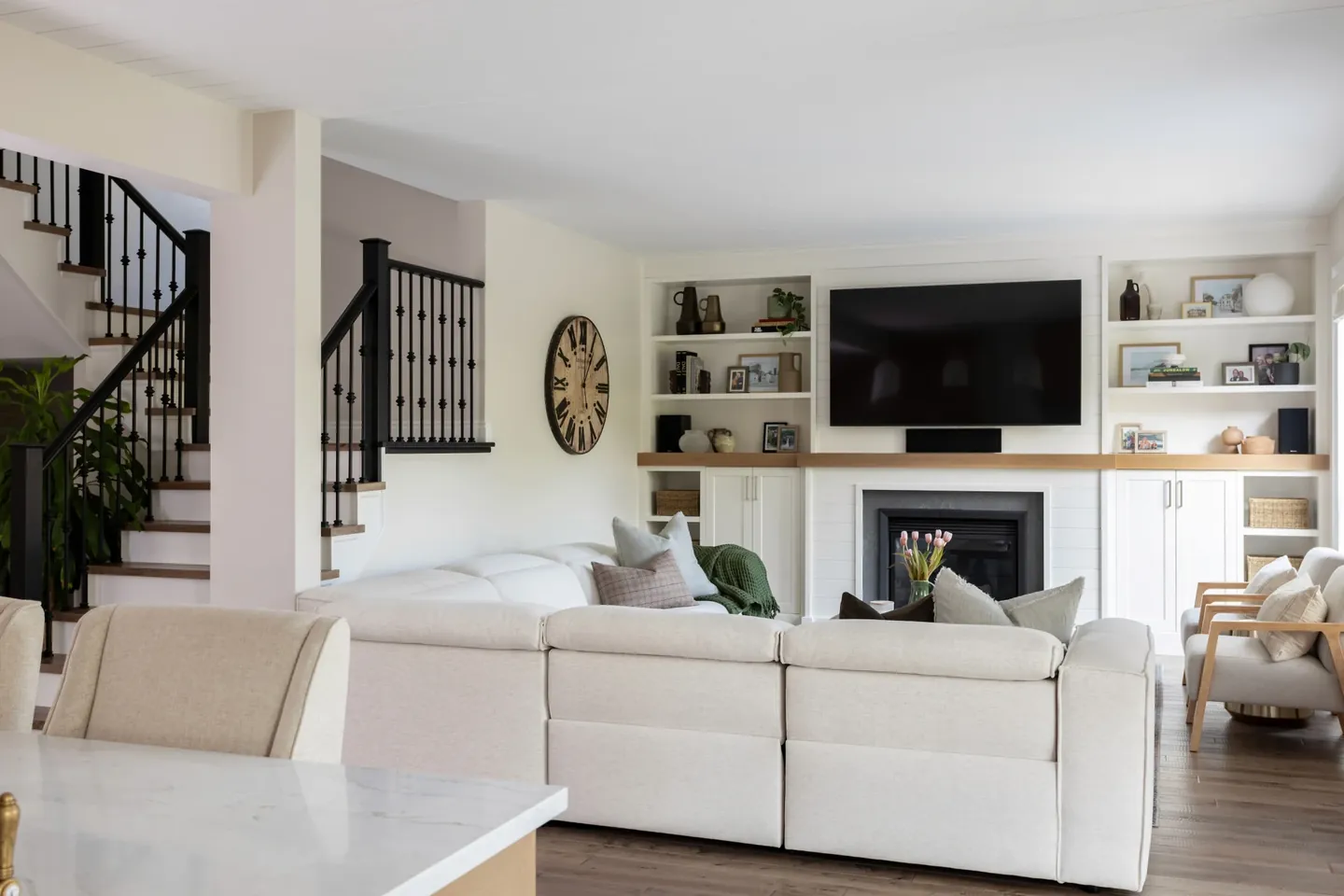 Family room with built-ins, a white sectional and a staircase beyond