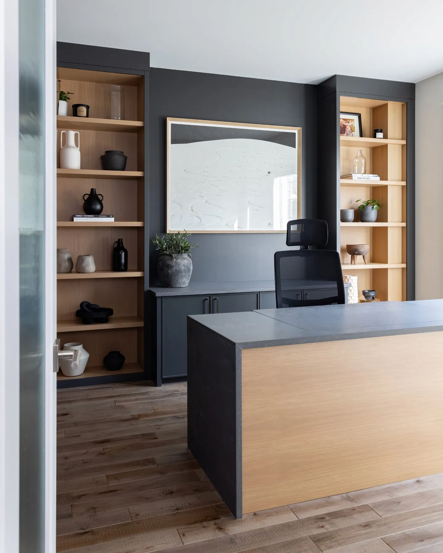 Charcoal home office with white oak shelving and a quartz-topped desk