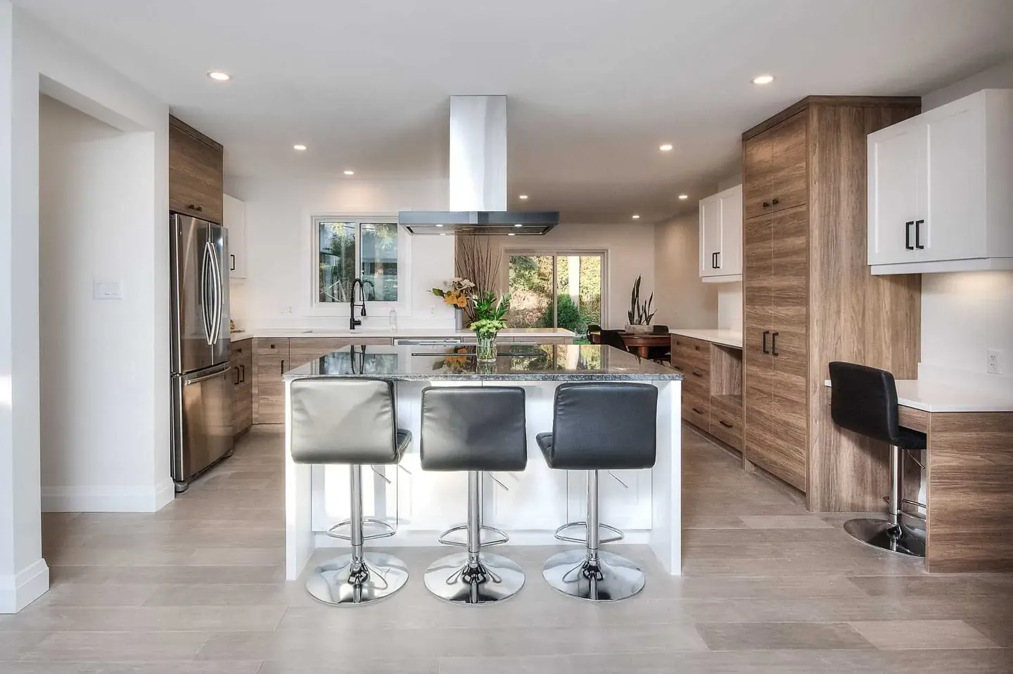 White kitchen with walnut accents, an island range hood and bar seating